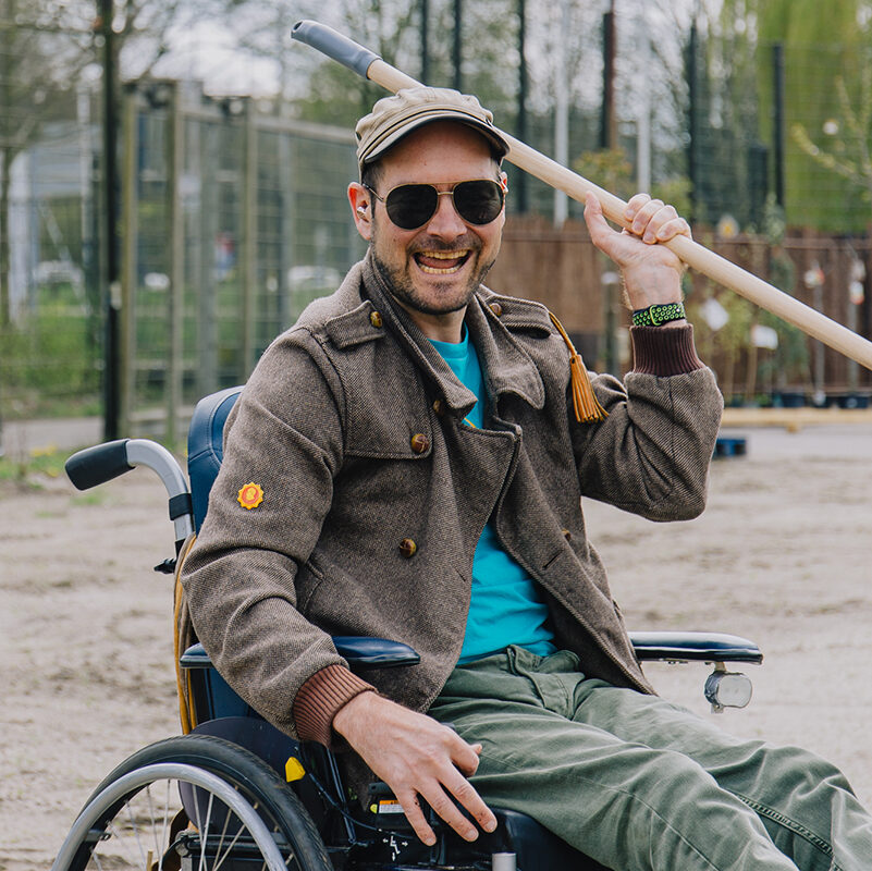 Medewerker van de Voedseltuin Overvecht bij Steck Utrecht heeft een schep in zijn hand. Hij heeft een zonnebril op en draagt een pet. Op de achtergrond is het terrein waar de voedseltuin komt te zien.