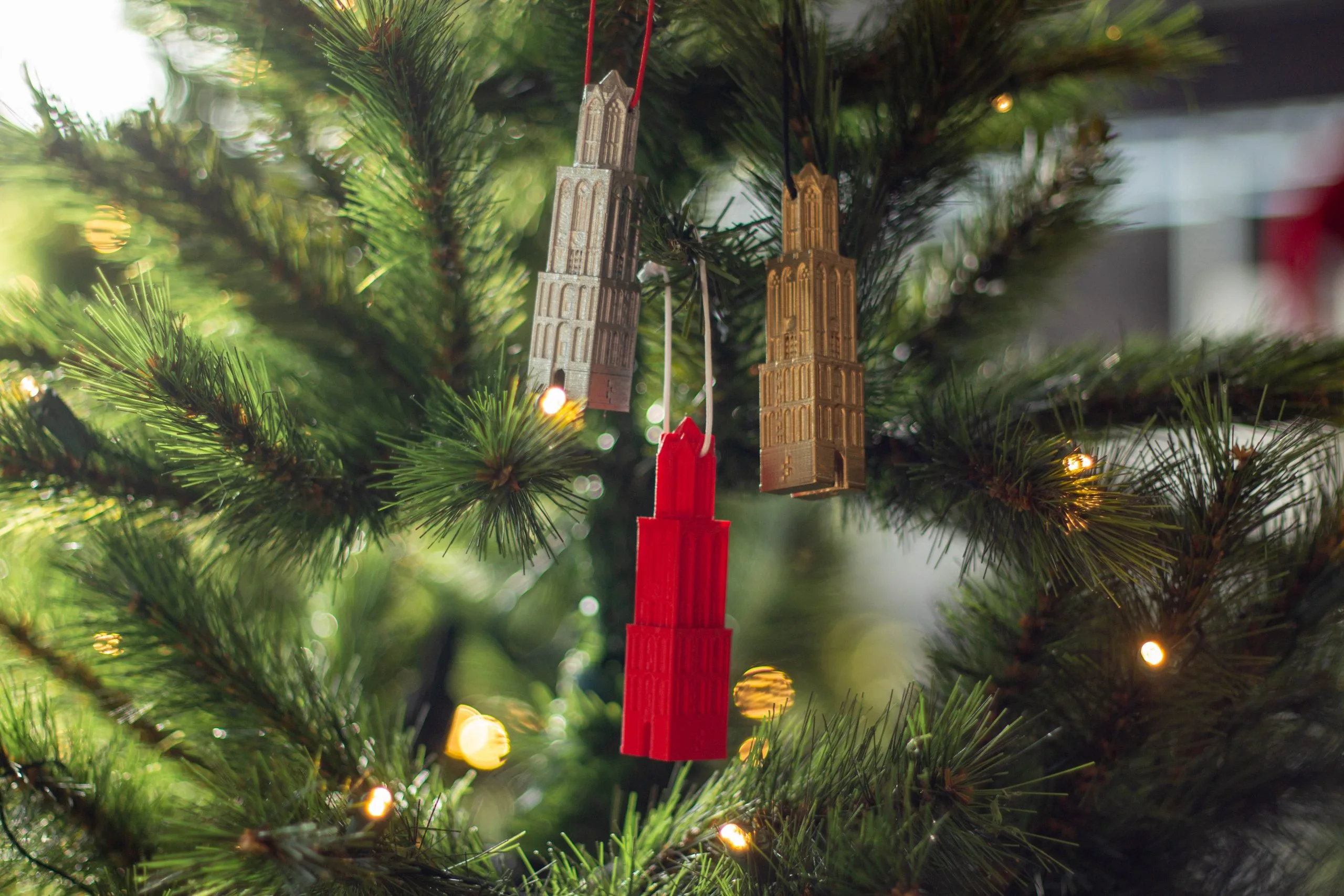 Kerstballen in de vorm van domtorens hangen in een kerstboom met lichtjes