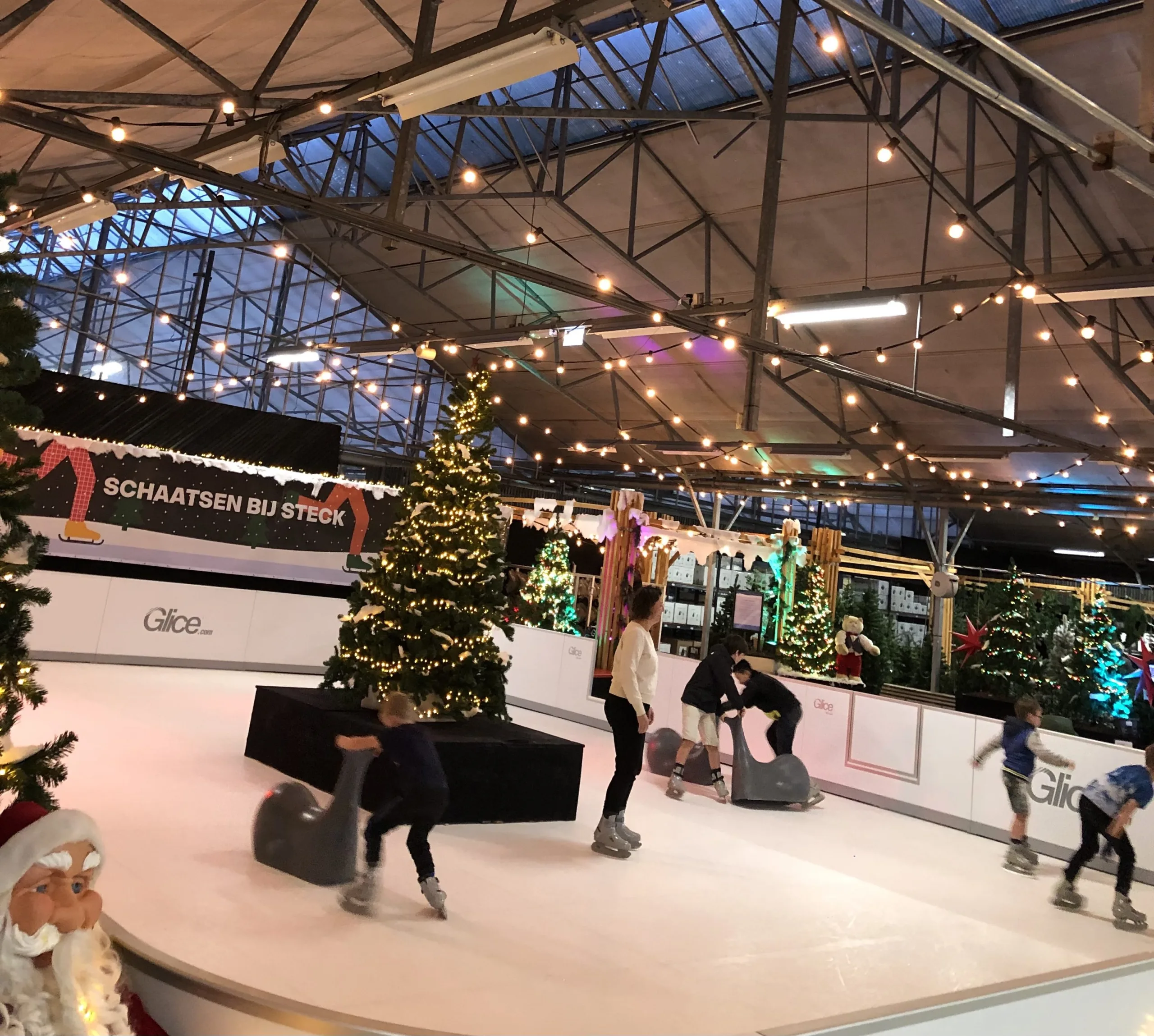 Een indoor schaatsbaan met een kerstboom in het midden